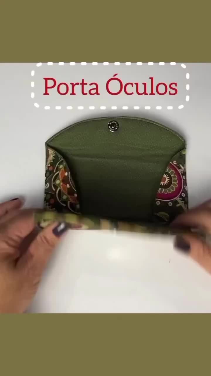 This may contain: two hands holding a green purse with the words porta oculos on it