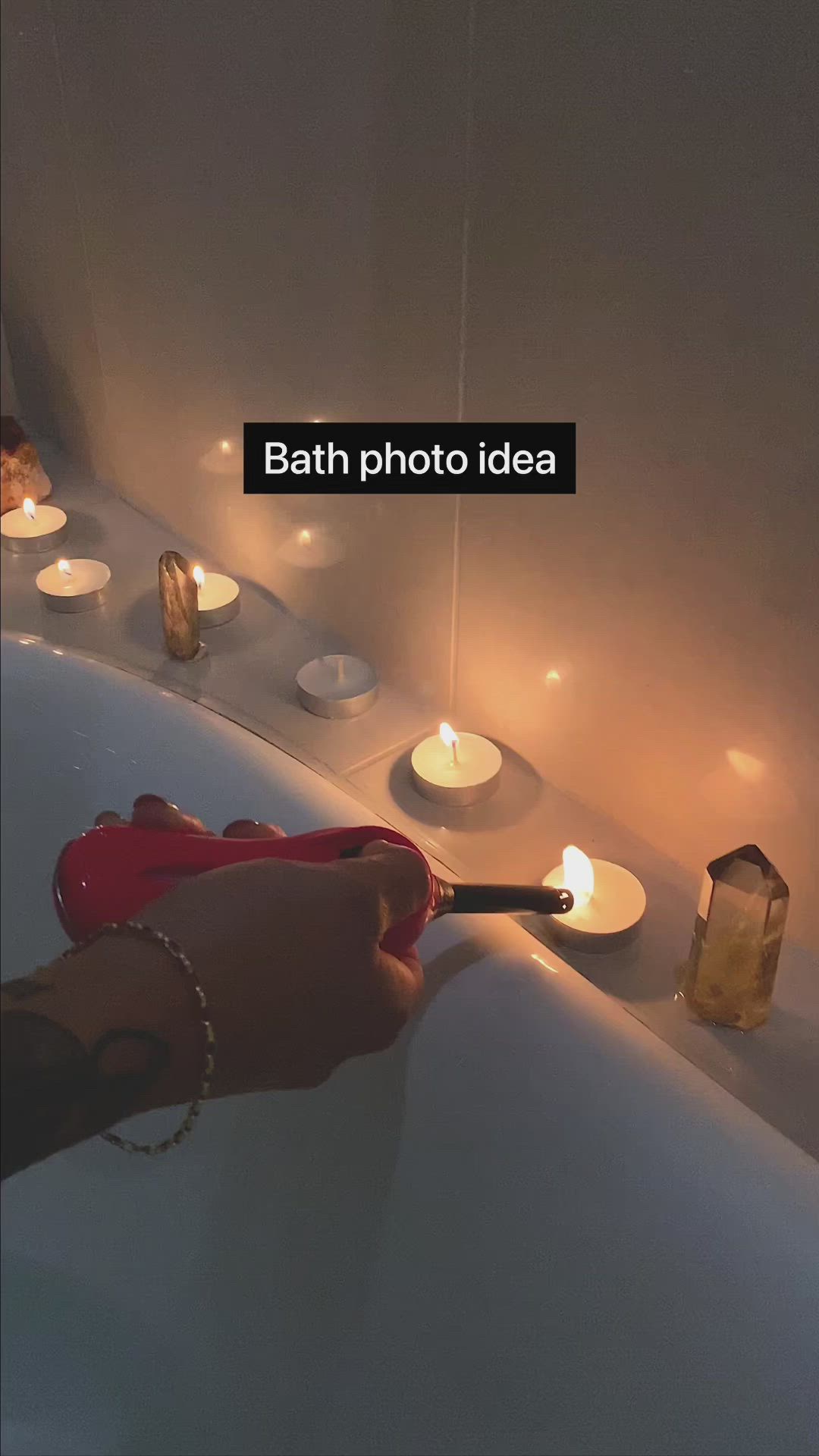 This may contain: a woman in a bathtub with candles around her and flowers floating on the water