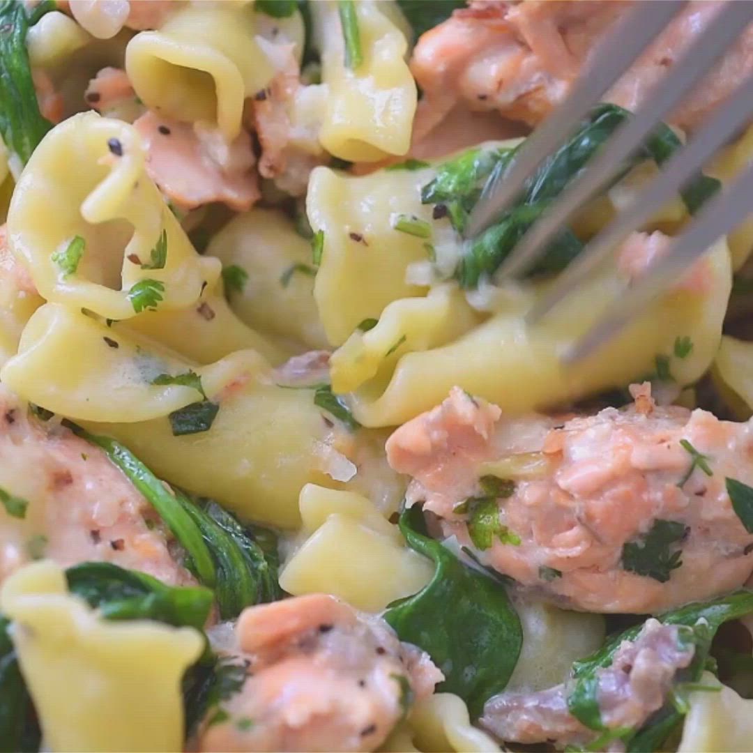 This may contain: a pasta dish with salmon and spinach