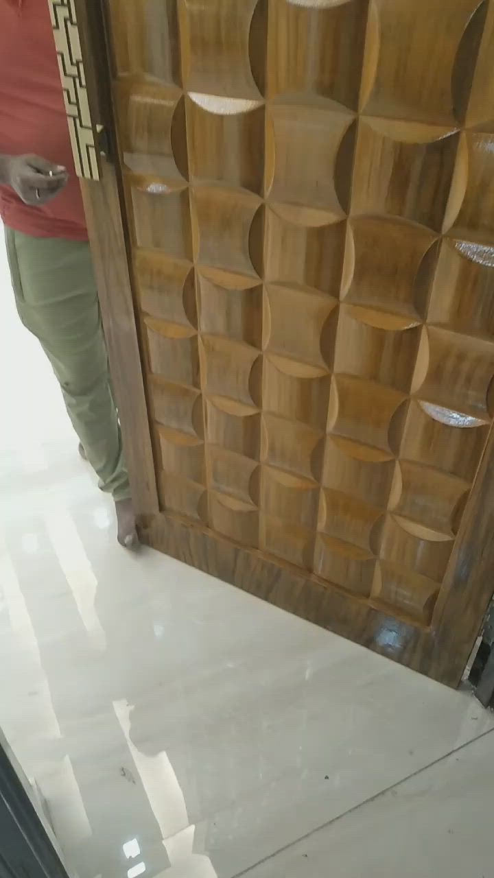 This may contain: a woman standing in front of a wooden door with white tiles on the floor and walls