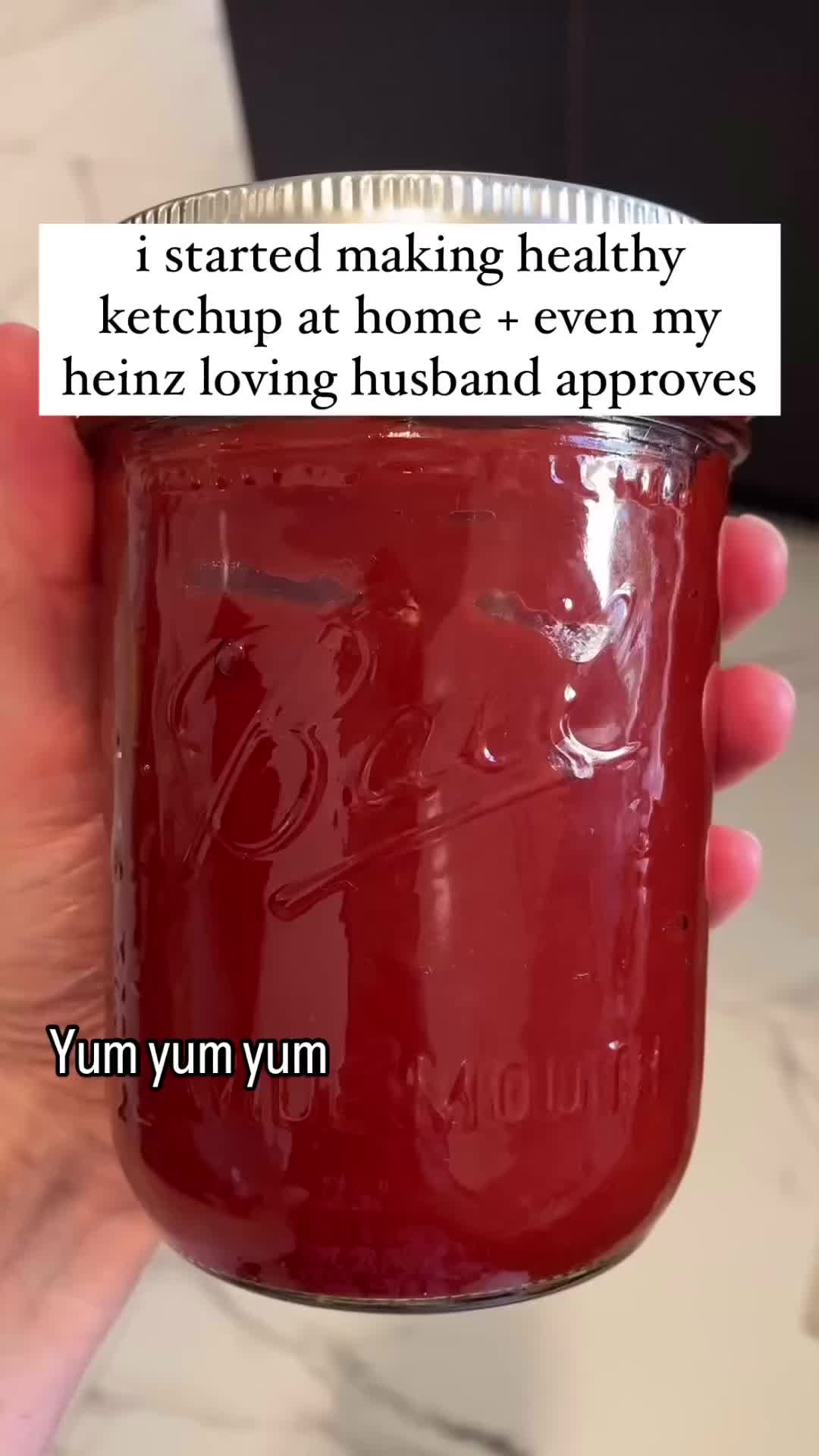 This may contain: a person holding a mason jar filled with ketchup next to a sign that reads, i started making healthy ketchup at home - even my henz loving husband approved