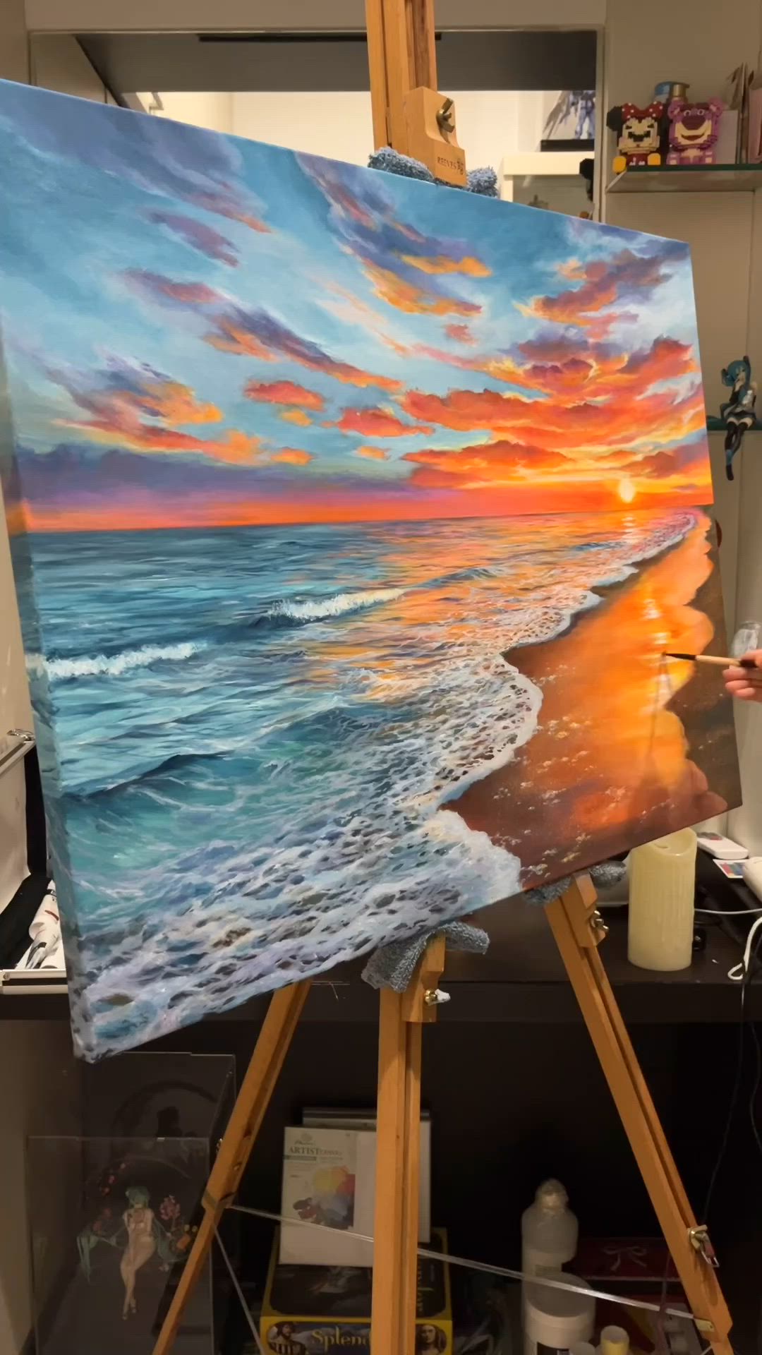 This may contain: a woman is painting on an easel in front of the sun setting over the ocean