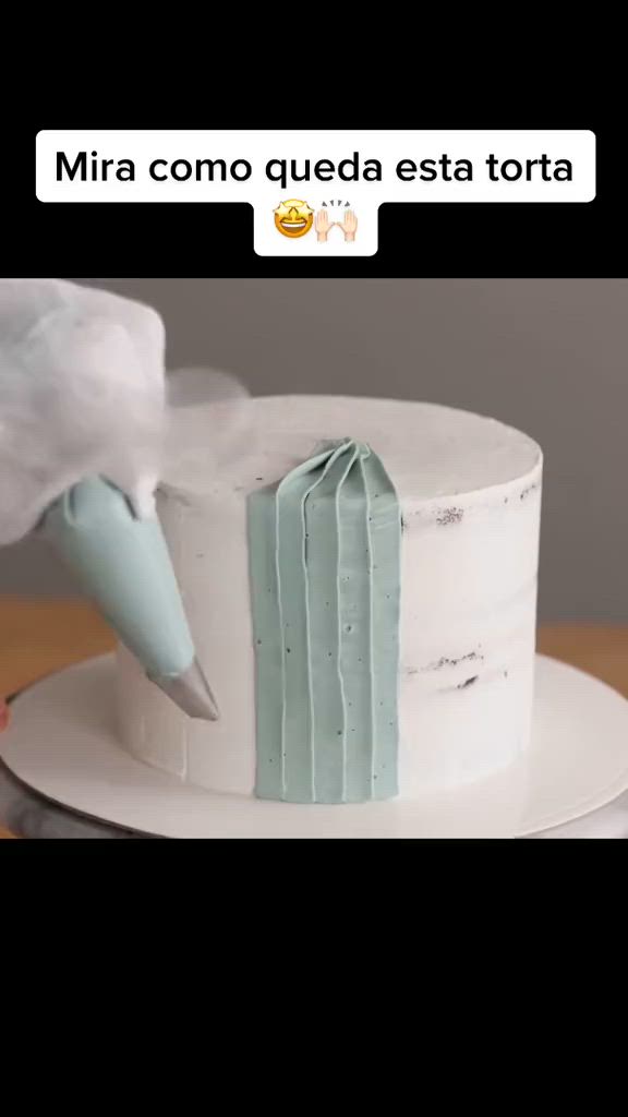 This may contain: a white cake with frosting on top and a person using a knife to cut it