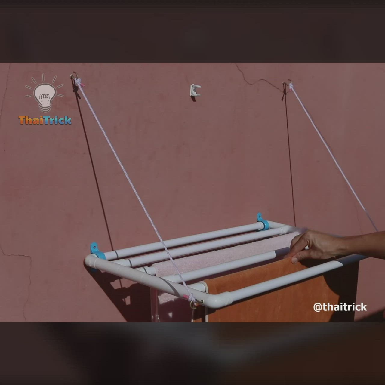 This may contain: a woman laying on top of a white bench next to a pink wall with wires