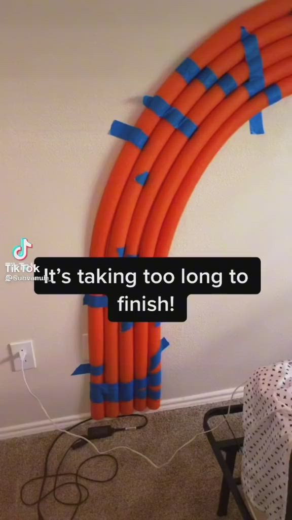 This may contain: an orange and blue balloon arch with the words it's taking too long to finish