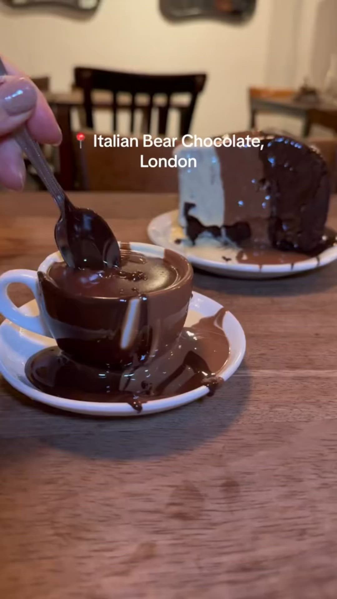 This may contain: a person is dipping chocolate into a cup with a spoon on the table in front of them