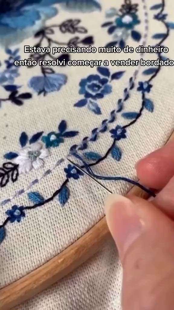 This may contain: someone is stitching flowers on a piece of fabric with a wooden needle and thread