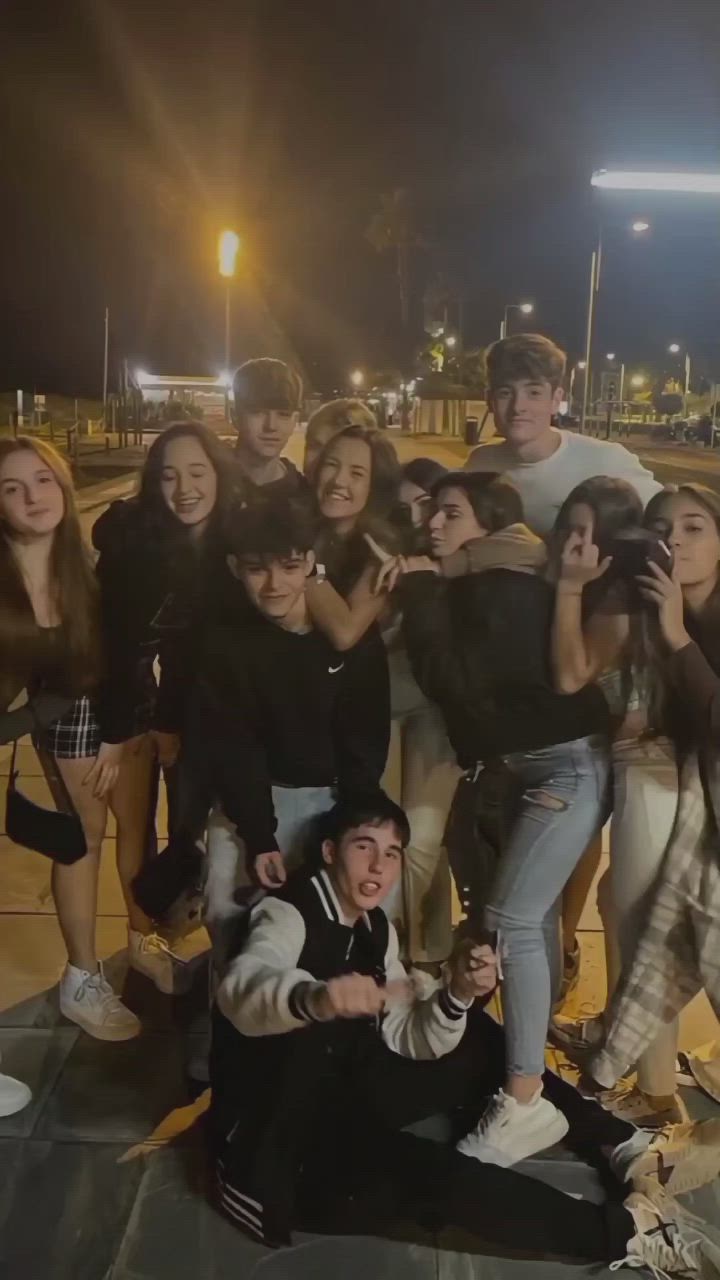 This may contain: a group of young people posing for a photo in front of an empty parking lot