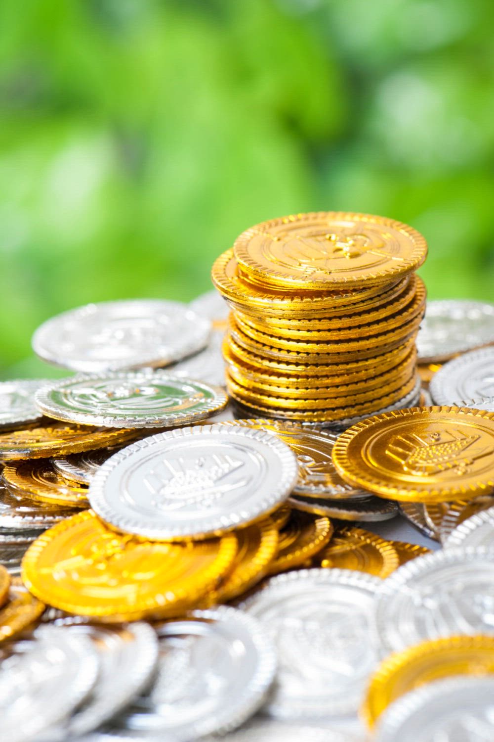 This may contain: a pile of gold coins sitting on top of a table next to a green background