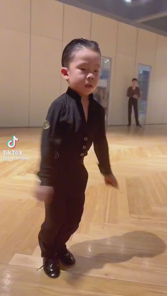 This may contain: a young boy standing on top of a hard wood floor