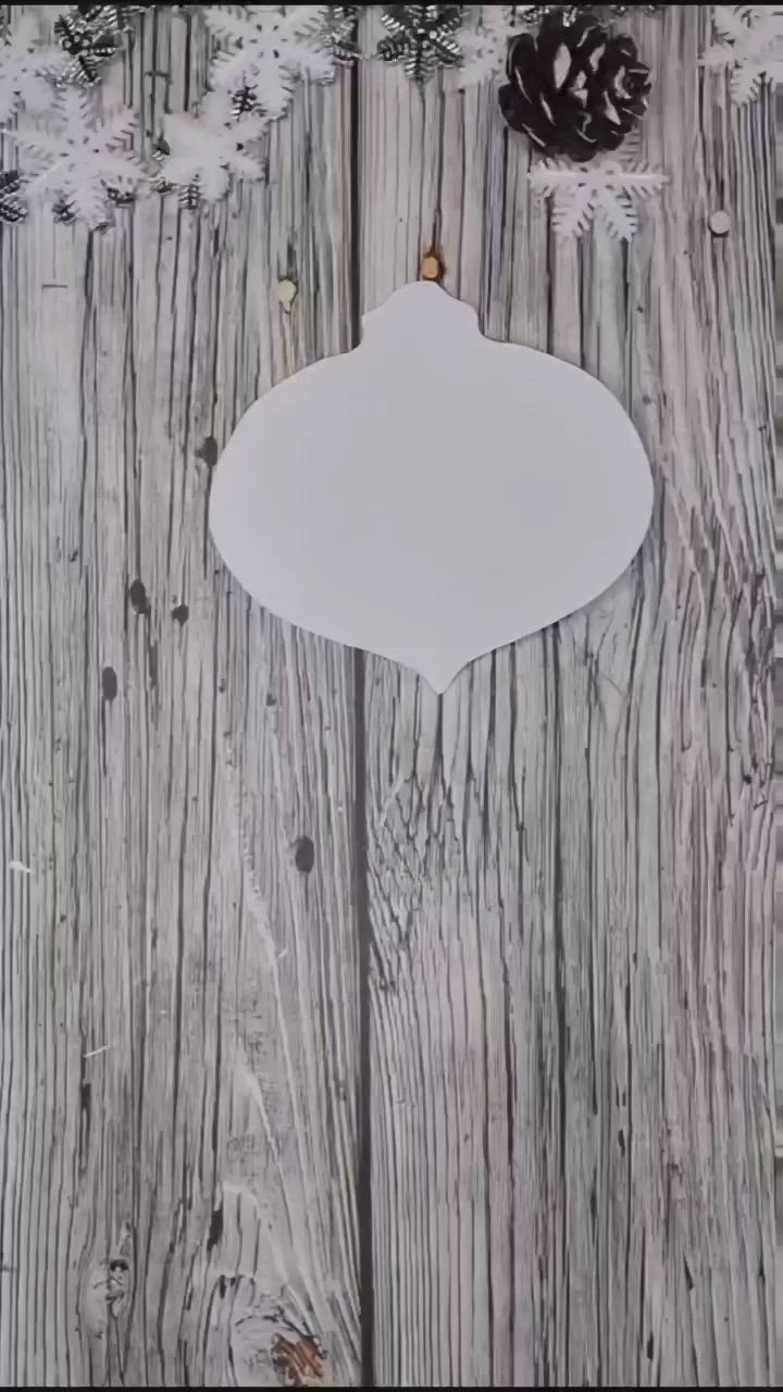 This may contain: a white ornament hanging on a wooden fence with pine cones and snow flakes