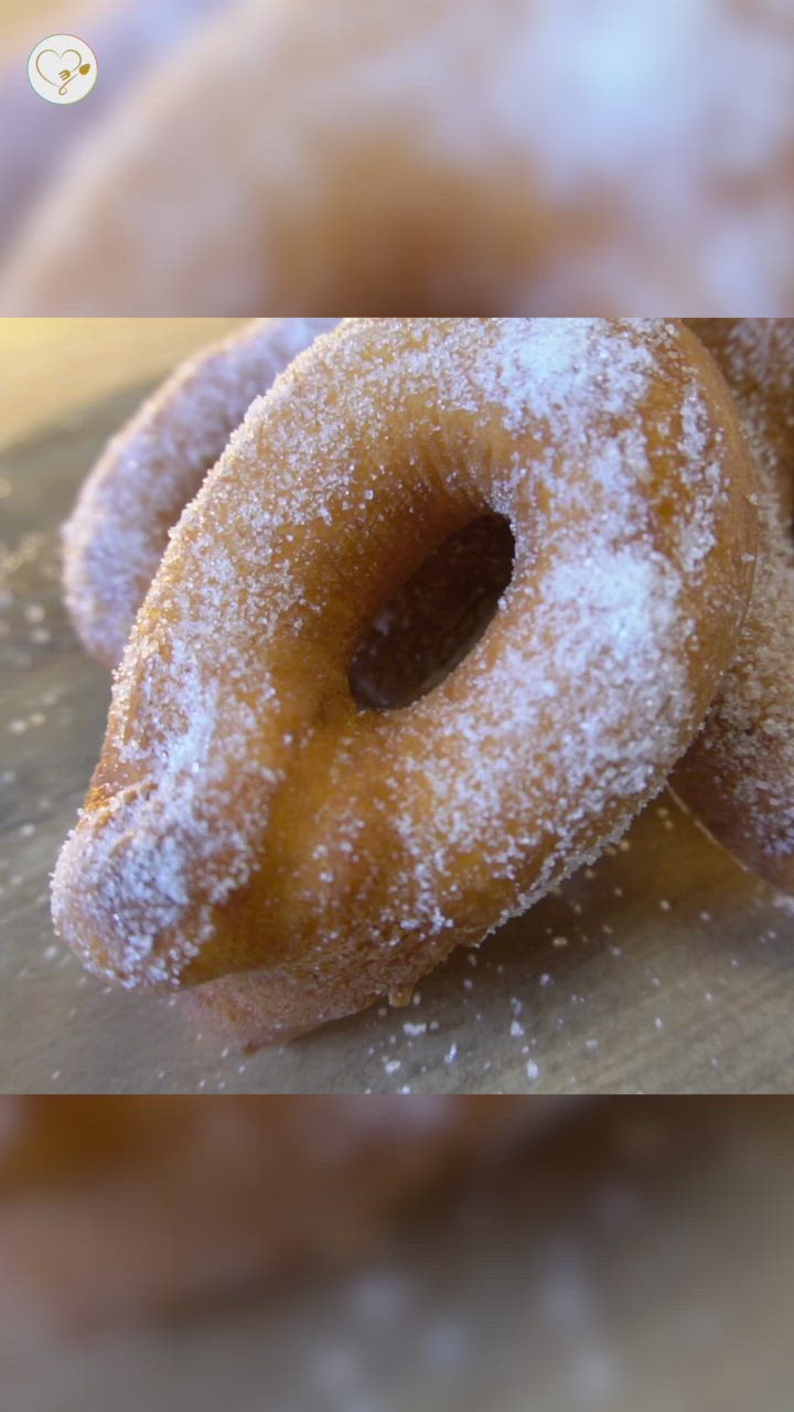 This may contain: two donuts covered in powdered sugar sitting on a table