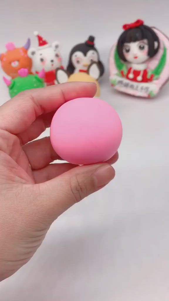 This may contain: a hand holding a small pink object in front of other toy figurines on a white surface