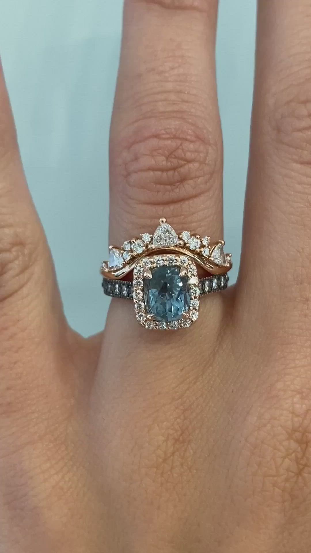 This may contain: a woman's hand with a blue and white diamond ring on top of it