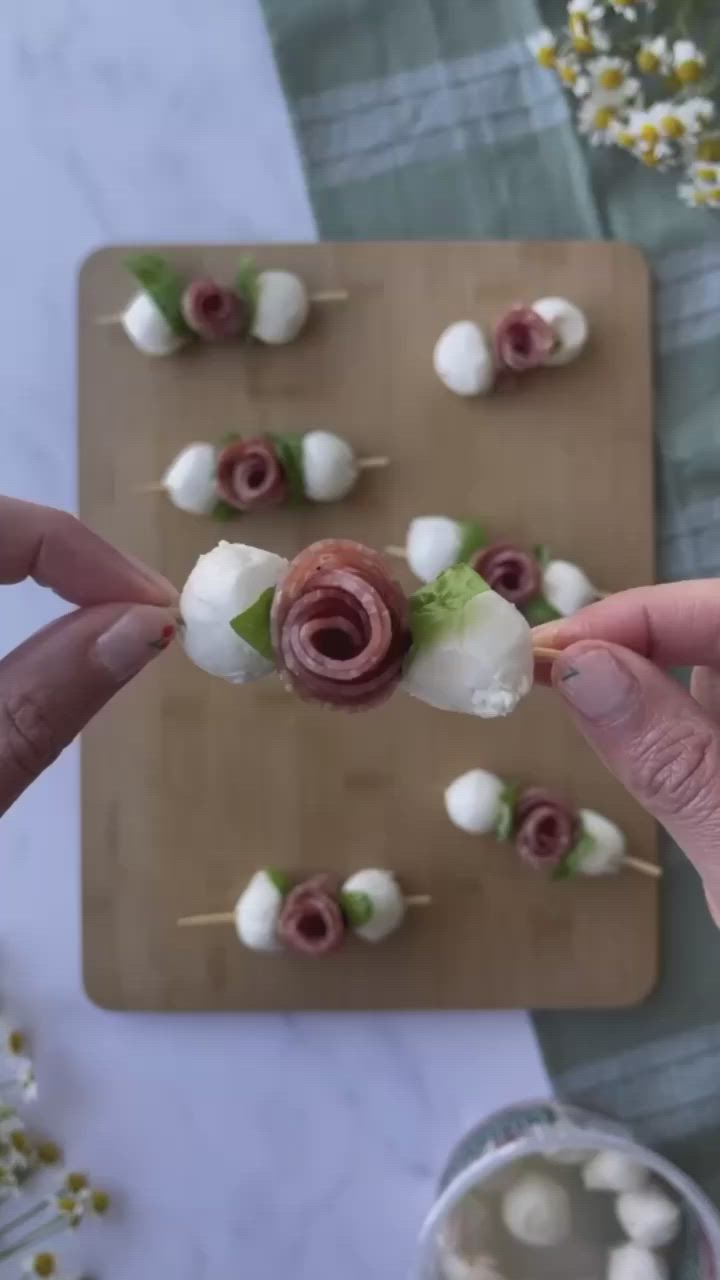 This may contain: someone is holding up some food on a stick with marshmallows and roses