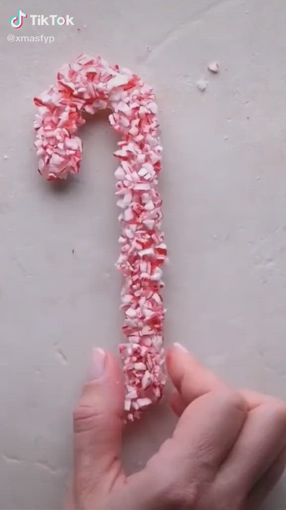 This may contain: someone is making a candy cane out of pink and white sprinkles on the surface