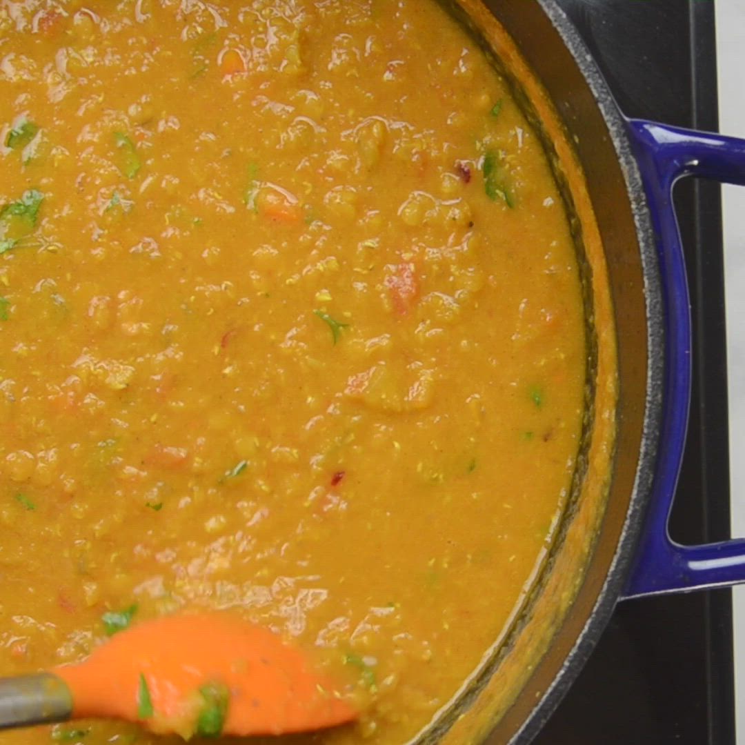 This may contain: a pot filled with soup on top of a stove next to an orange spatula