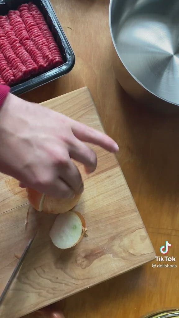 This may contain: a person is holding a spoon over a bowl of food on a table with utensils