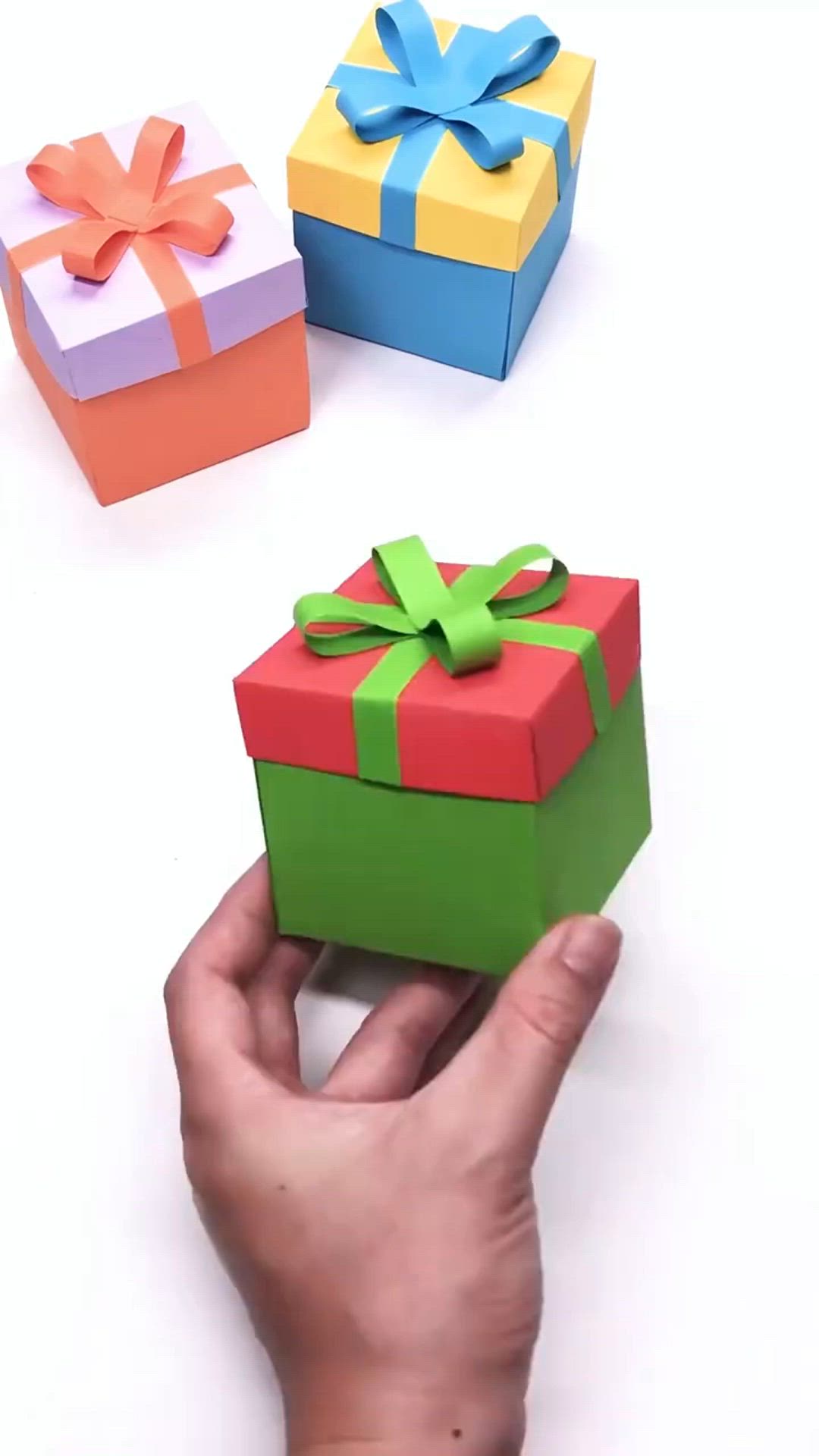 This may contain: someone is holding a small gift box in front of two smaller boxes on the table