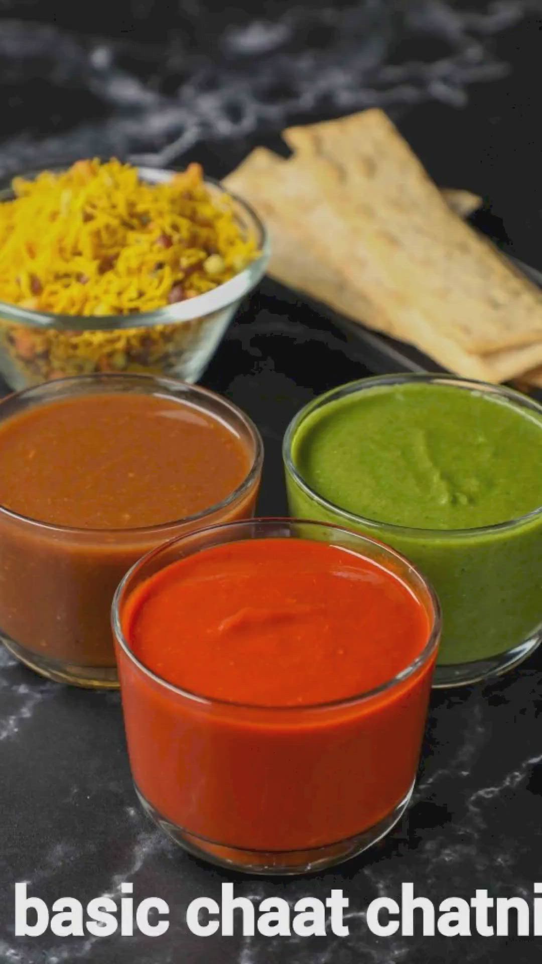 This may contain: three bowls filled with different colored sauces on top of a black counter next to bread sticks