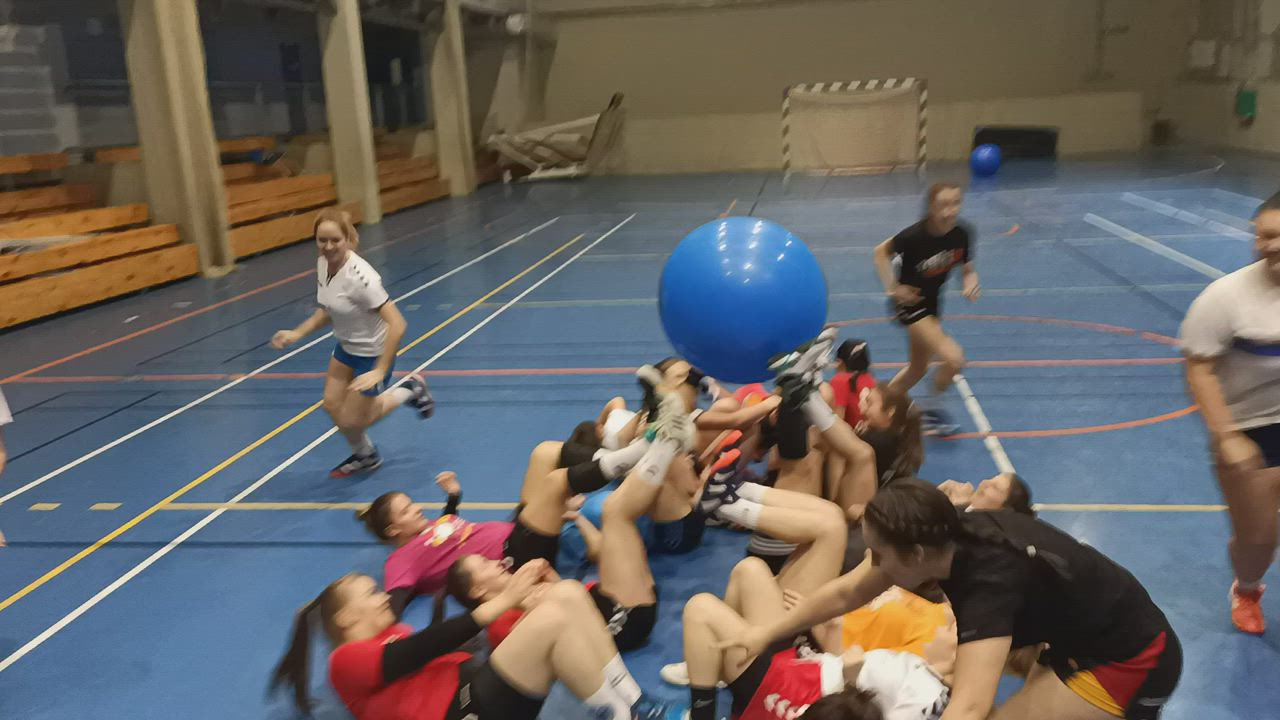 This may contain: a group of people in a gym with one person holding a ball and the other sitting on the floor