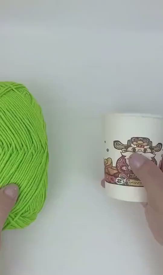 This may contain: someone is holding a green yarn ball next to a coffee cup