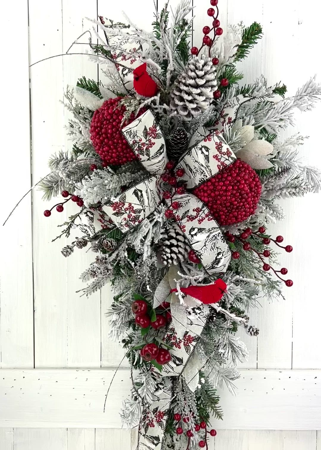 This may contain: a christmas wreath with red berries and pine cones