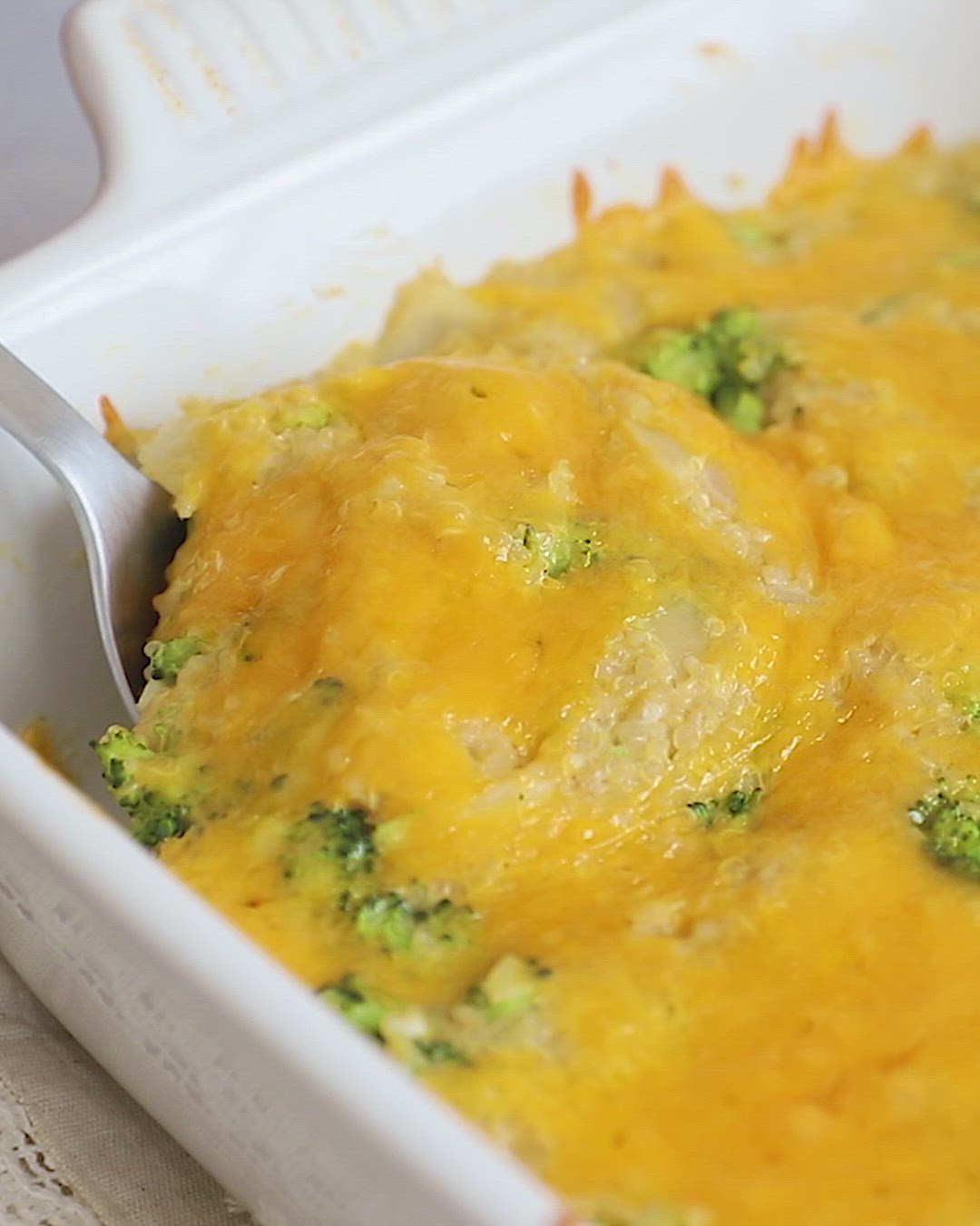 This may contain: a casserole dish with broccoli and cheese being lifted from the casserole