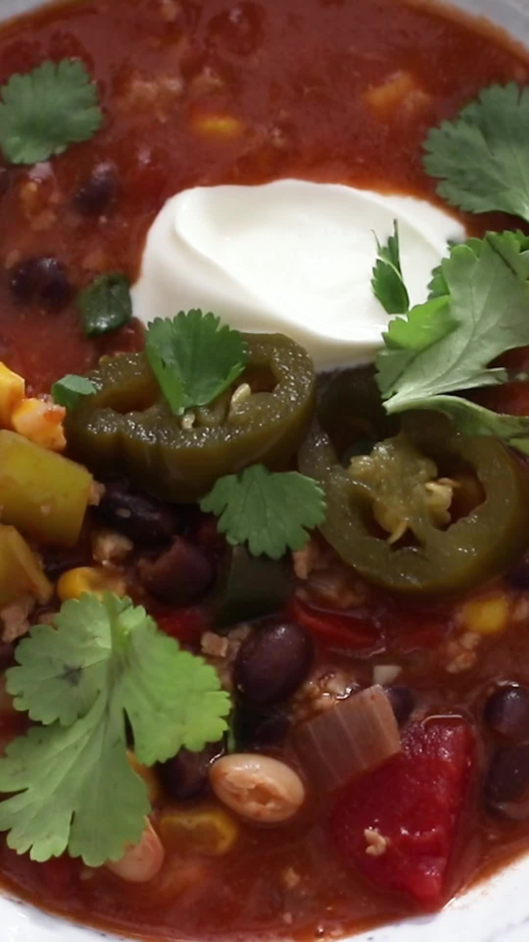 This may contain: healthy turkey chili in a white bowl with cilantro