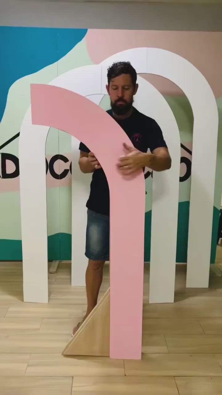 This may contain: a man standing in front of a pink and white sculpture that looks like a letter