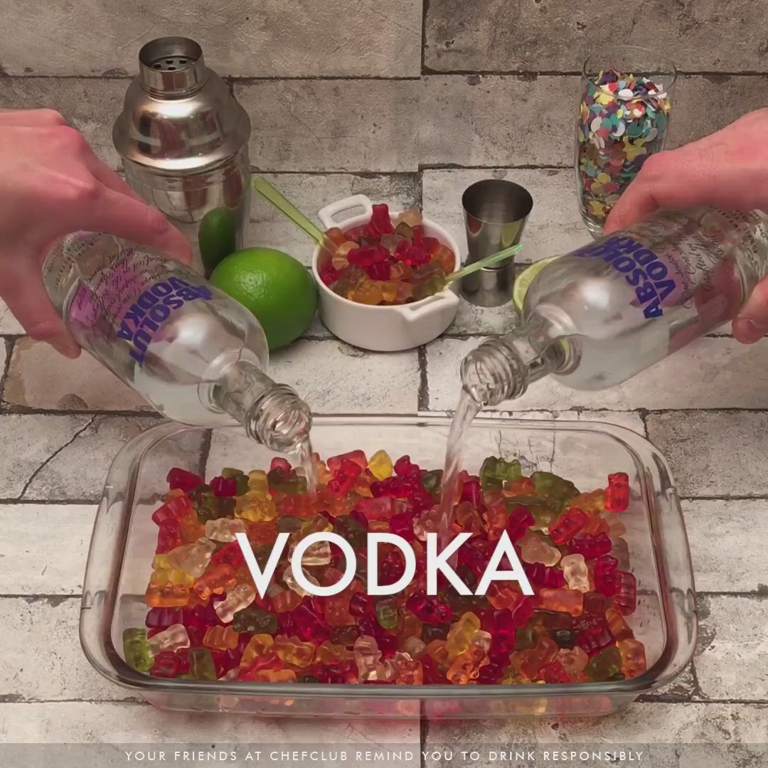 This may contain: two hands are pouring vodka into a container filled with gummy bears and other candies