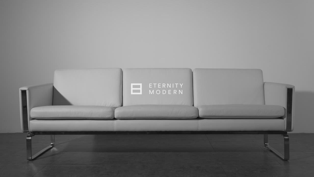 This may contain: a white couch sitting on top of a hard wood floor next to a gray wall