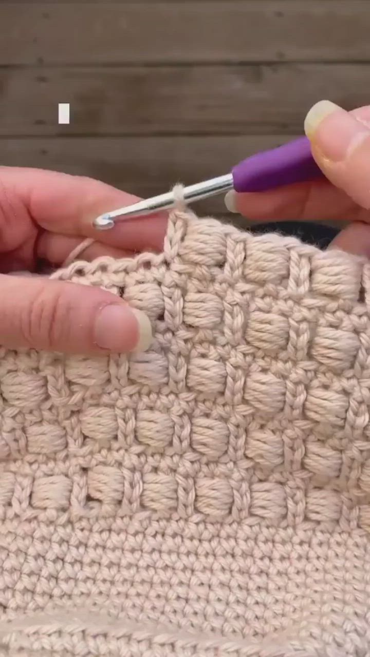 This may contain: two hands crocheting the ends of a piece of fabric