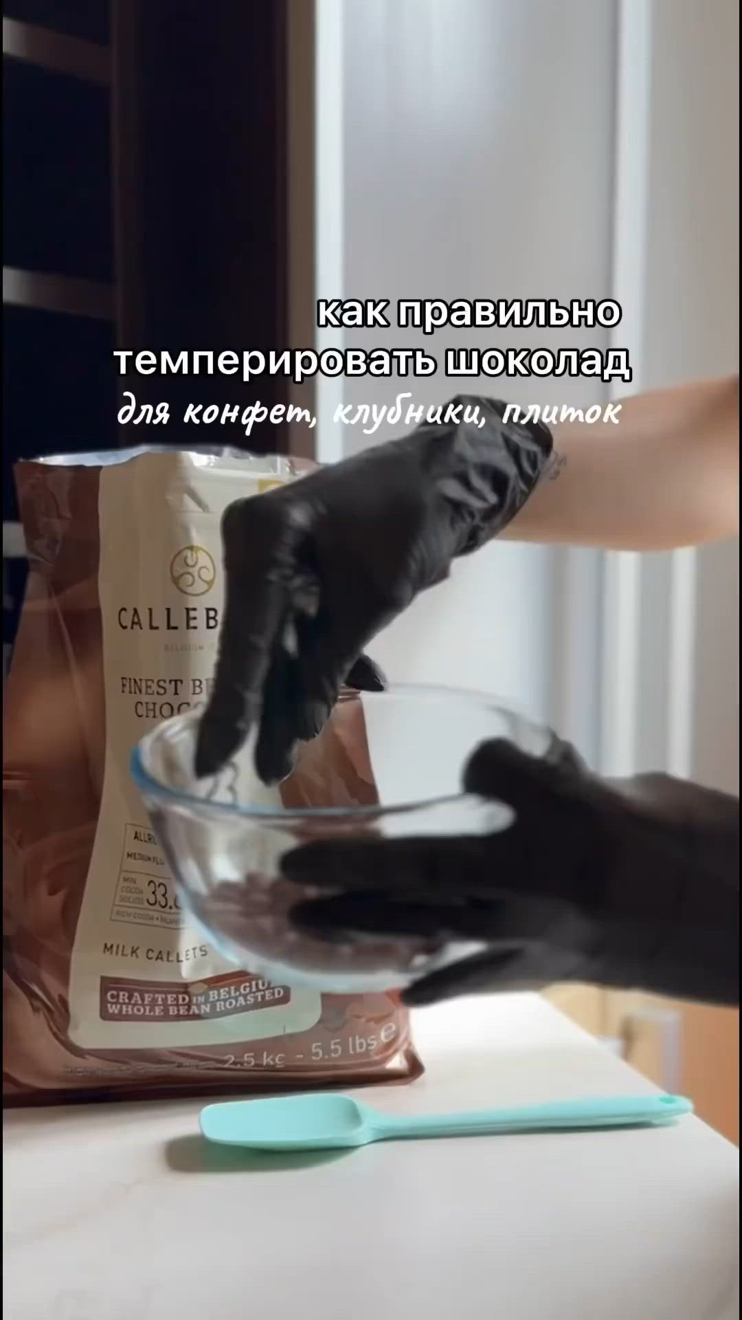 This may contain: two hands in black gloves are mixing something in a glass bowl on a counter top