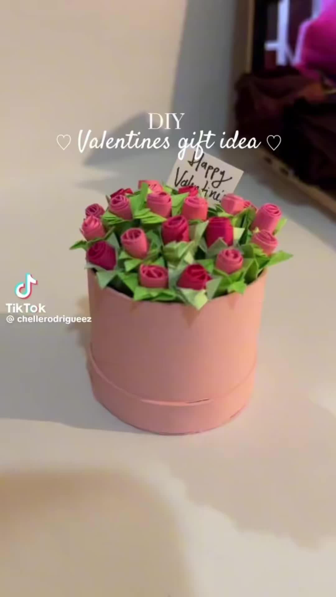 This may contain: a pink flower pot with red roses in it and a sign that says valentine's gift idea