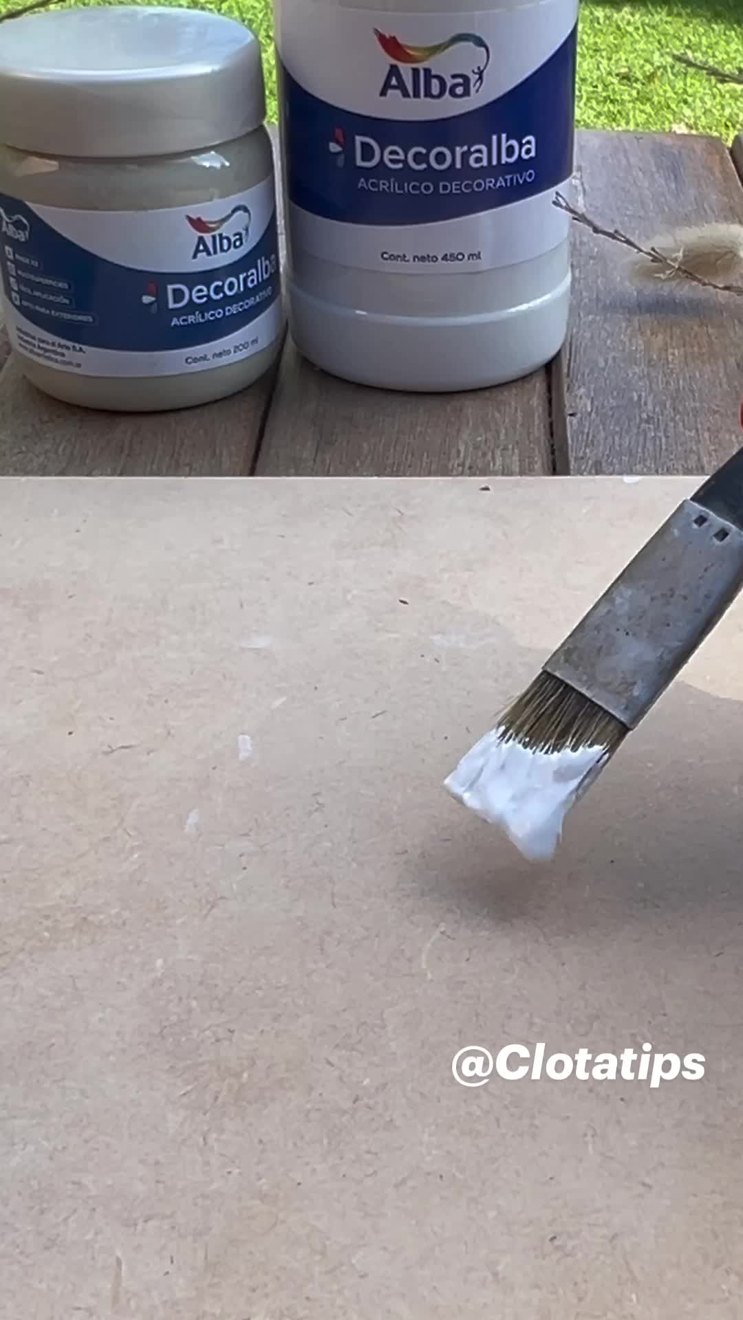 This may contain: someone using a paint brush to paint the outside of a table with white paint on it