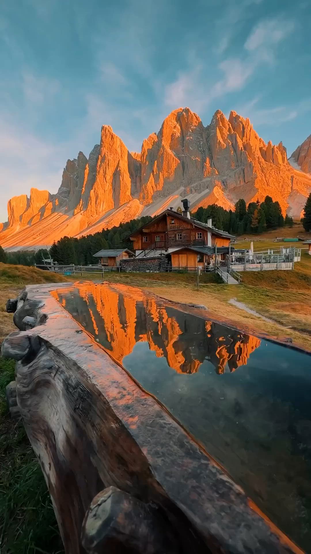 This may contain: a wooden bench sitting next to a body of water in front of a mountain range