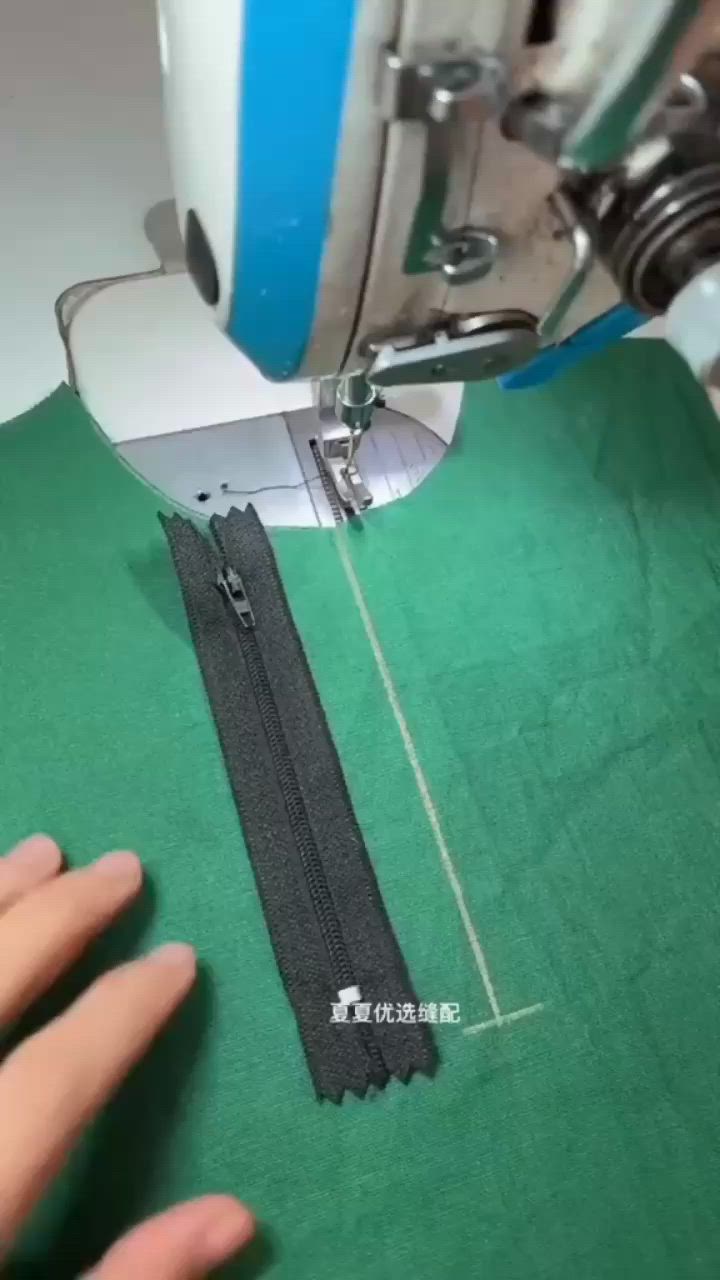 This may contain: someone is using a sewing machine to sew something on a green cloth with scissors