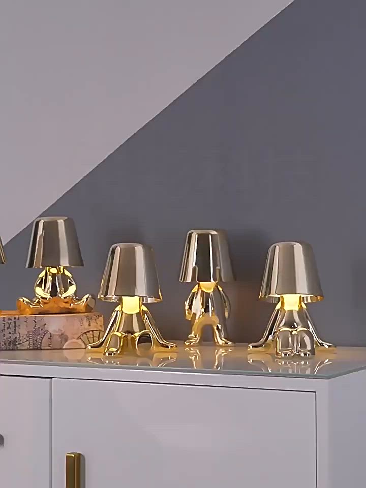 This may contain: four gold lamps sitting on top of a white dresser next to a wall with a gray background