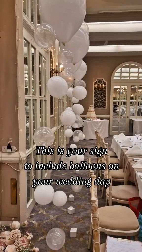 This may contain: balloons are floating down from the ceiling at a wedding