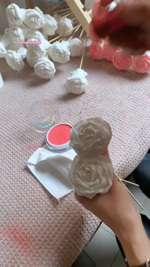 This may contain: someone is making soap flowers out of toilet paper on a table with other items in the background