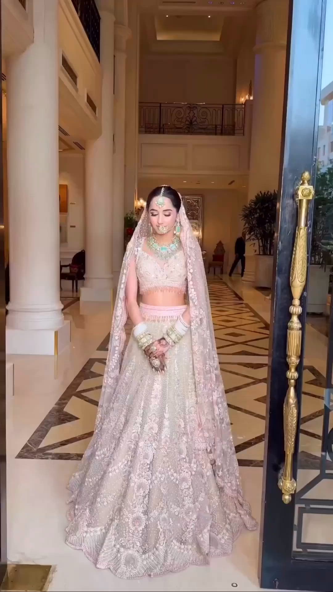 This may contain: a woman in a bridal gown standing at the entrance to a building