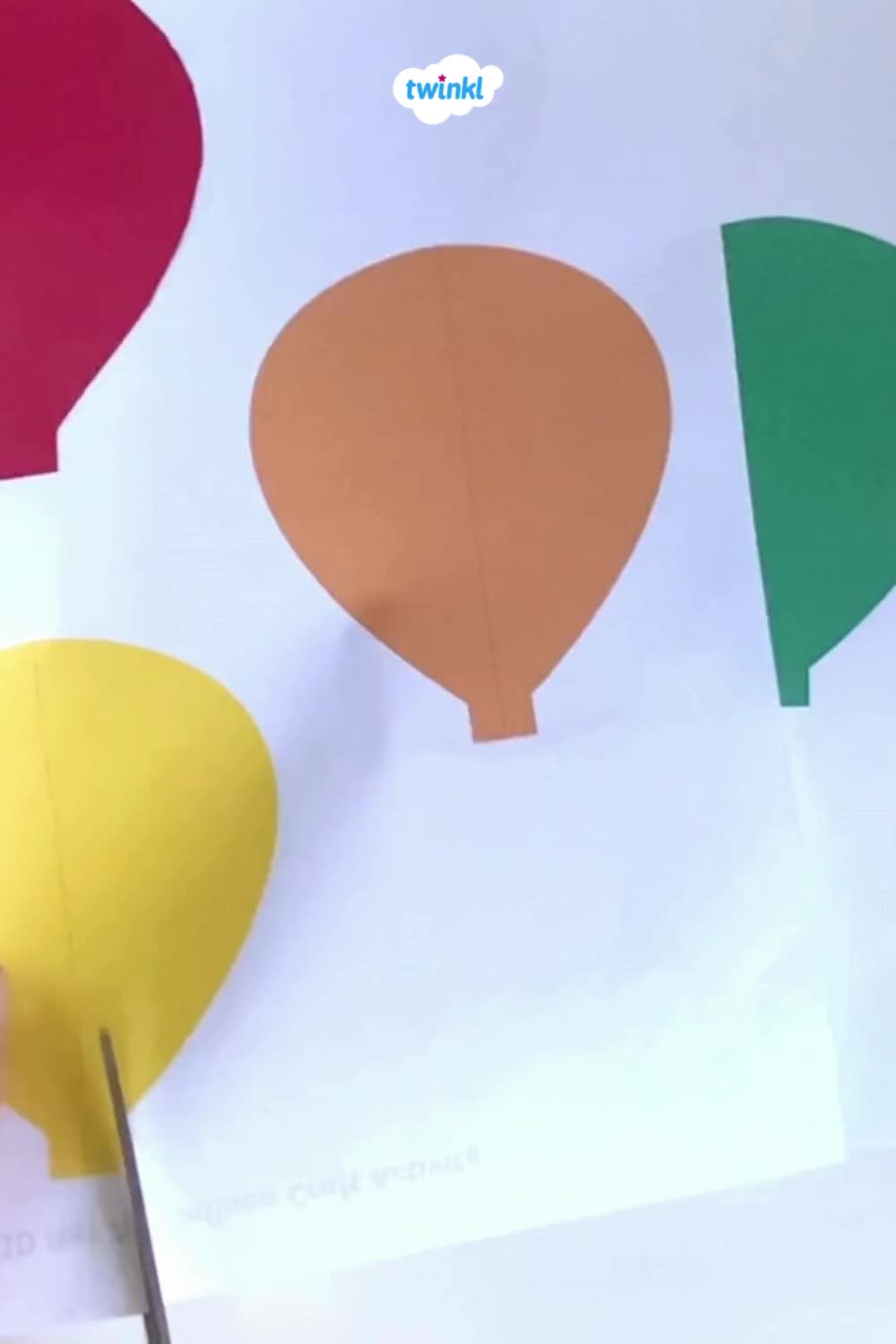 This contains: Video shows hands making a DIY paper hot air balloon craft aimed at kids. The balloon is red, yellow, green, orange, and blue.