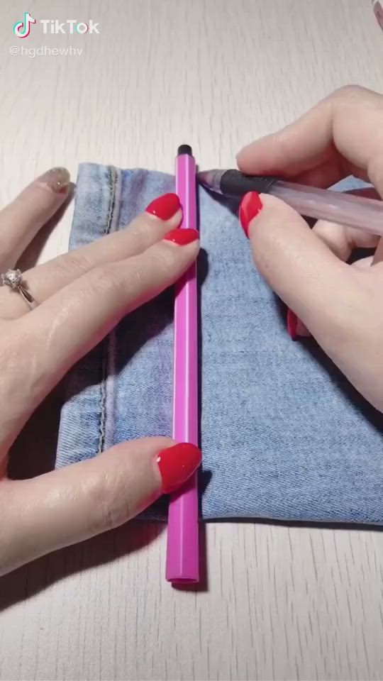 This may contain: two hands with red nail polish on their nails and one hand holding a pink pencil