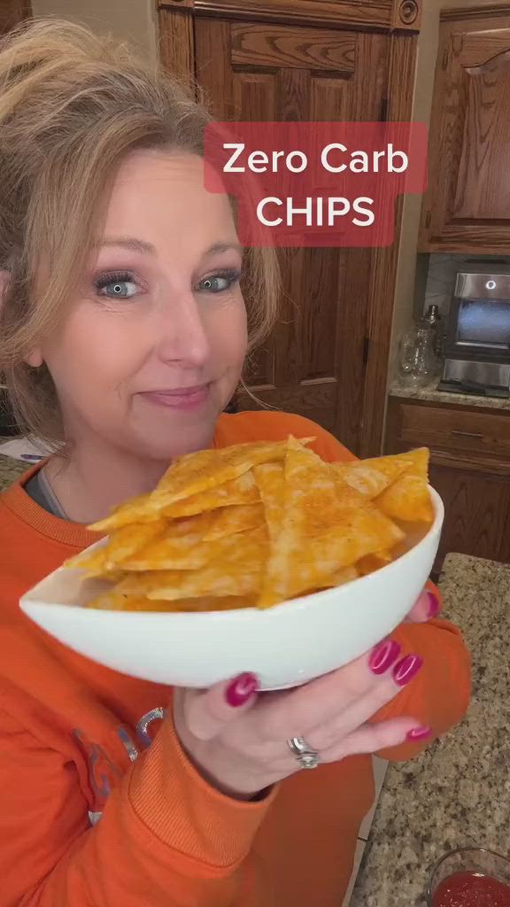 This may contain: a woman holding a plate full of chips with the caption zero carb chips