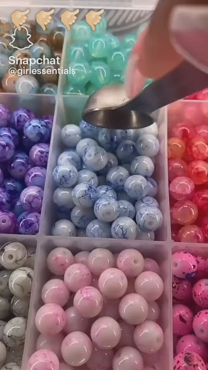 This may contain: there are many different colors of beads in the bins and someone is using a spoon to mix them together