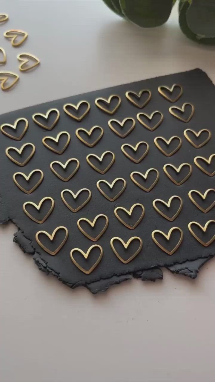 This may contain: a piece of black leather with gold hearts cut out of it on a white table