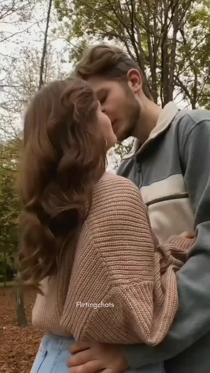 This may contain: a man and woman kissing in the woods