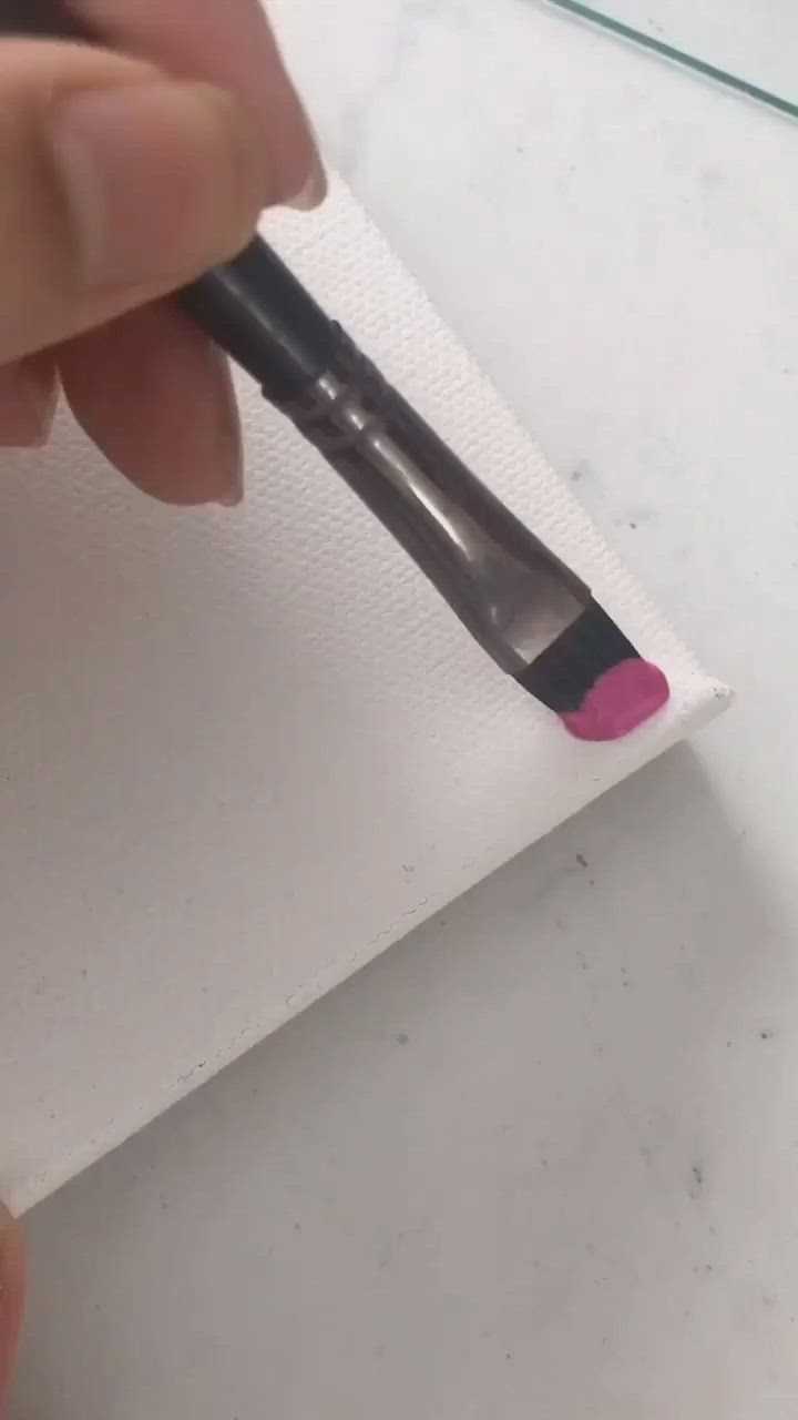 This may contain: someone is using a brush to paint the paper with pink and purple colors on it