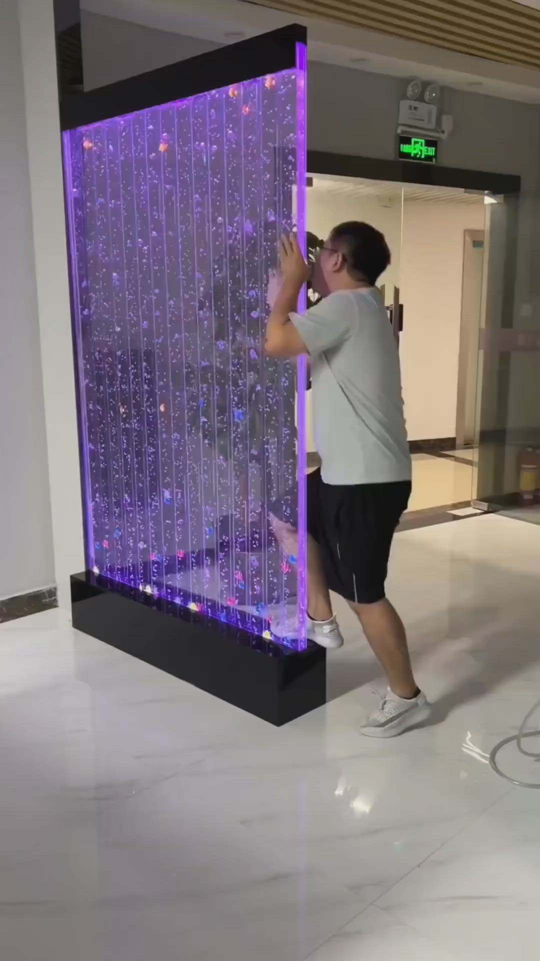 This may contain: a man standing in front of a purple glass wall with rain drops all over it